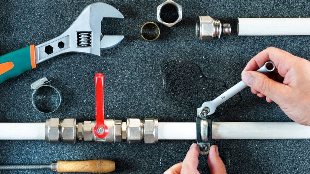 Plumber repairing a pipe valve with an adjustable wrench in Fayetteville