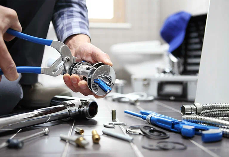 Technician repairing a plumbing fixture with professional tools in Fayetteville