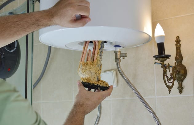Technician removing mineral buildup from a water heater in Fayetteville