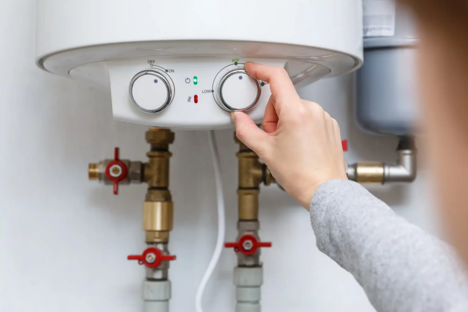 Homeowner adjusting the temperature controls on a water heater in Fayetteville